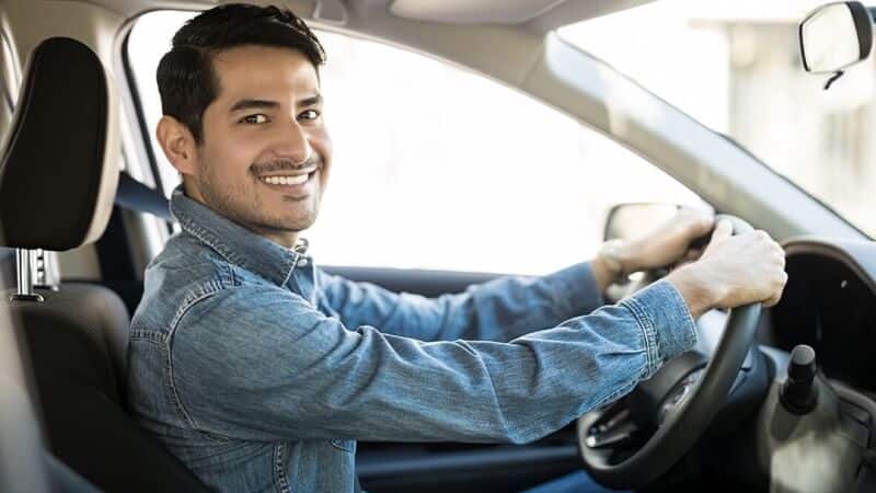Shop Marketing Pros: Hammond, La.; "How Can My Auto Repair Shop be Promoted to Both English & Spanish Speaking Consumers?" Handsome latin male sitting in the driverseat of his car smiling with both of his hands on the steering wheel
