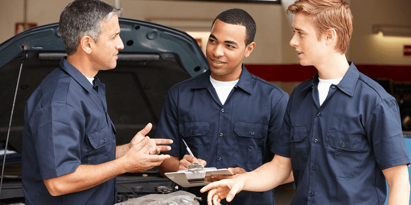 Ready to Start Investing in Your Employees? with AutoFix Auto Shop Coaching's Chris Cotton; image of auto repair shop owner training new mechanics about engine